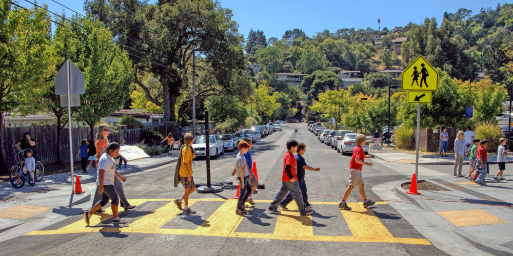 Image of school children crossing a residental street in a yellow painted crosswalk
